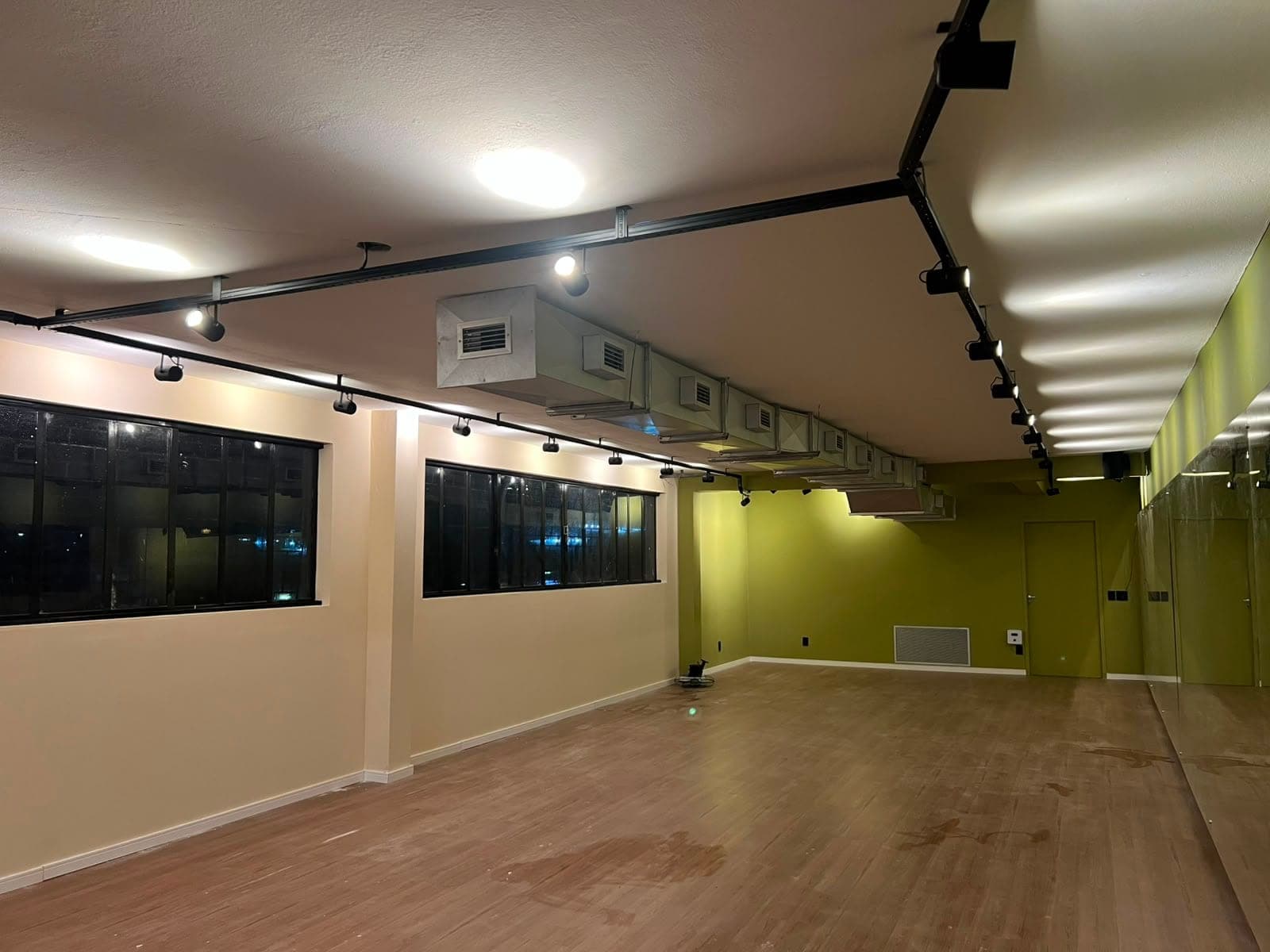 Sala de hot yoga do Hikari em ângulo amplo, com janelas e trilho de iluminação.