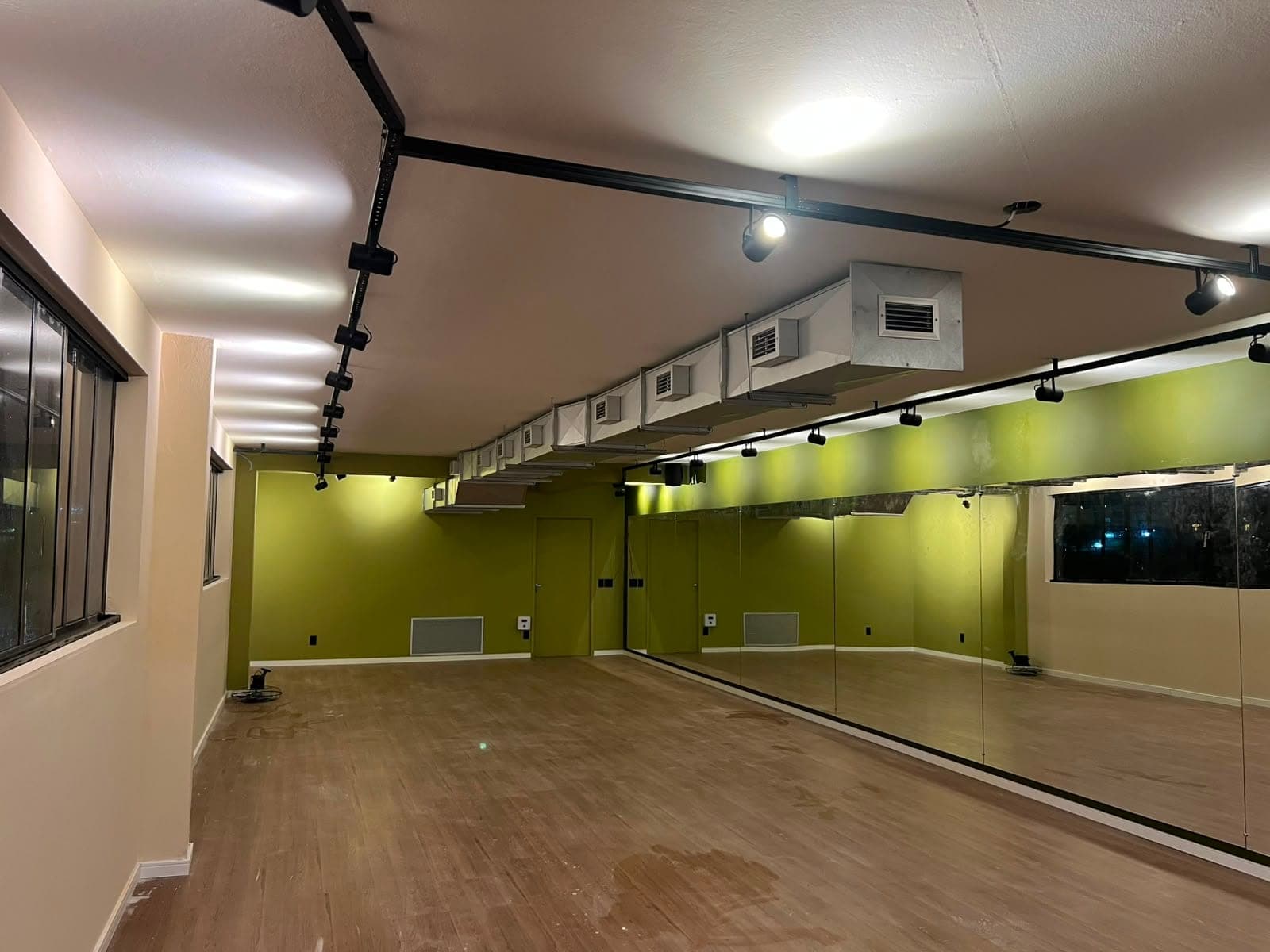 Sala de hot yoga do Hikari com parede espelhada e piso de madeira.